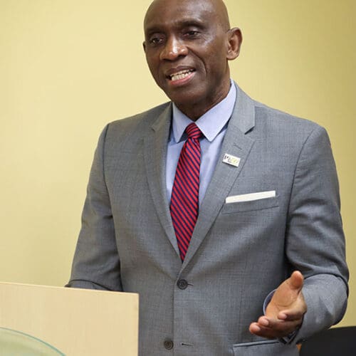 Pat Obi stands at a College of Business podium and talks