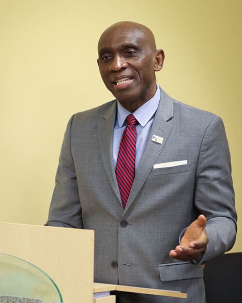 Pat Obi stands at a College of Business podium and talks