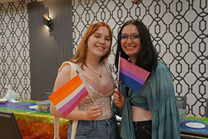 Two students post together and hold up pride flags