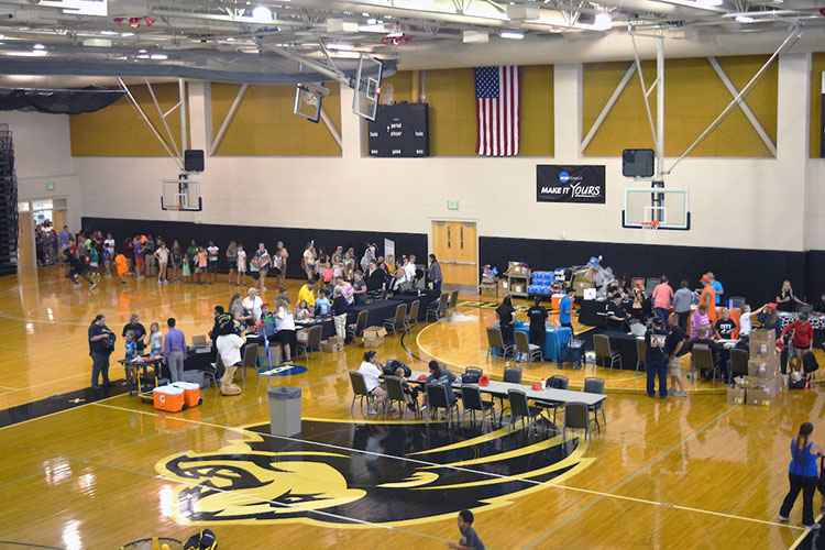 People line up in a gym to receive school supplies.