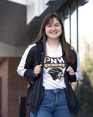 A female PNW student in a PNW Pride t-shirt outdoors