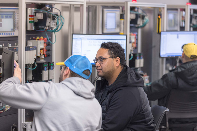 Two students sit at computers in a mechatronics class