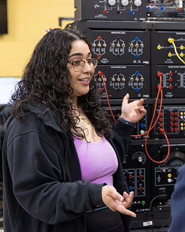 A female student talks in front of technical equipment