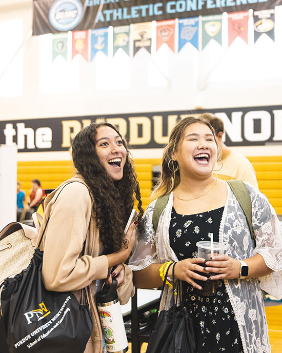 Two students smile together in a gym