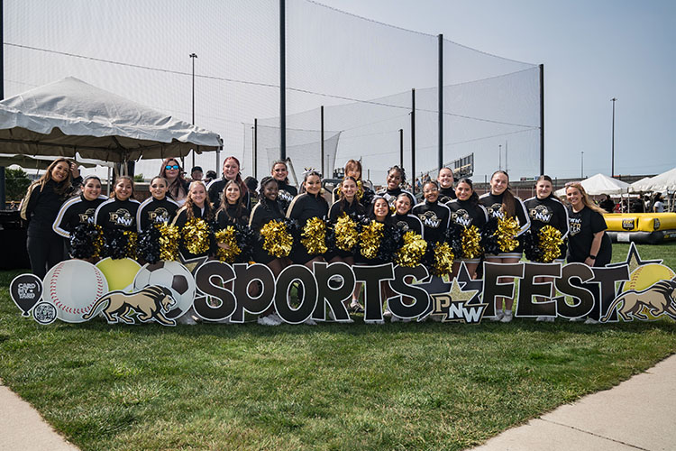 PNW Dance and Cheer teams pose behind a "Sports Fest" yard sign