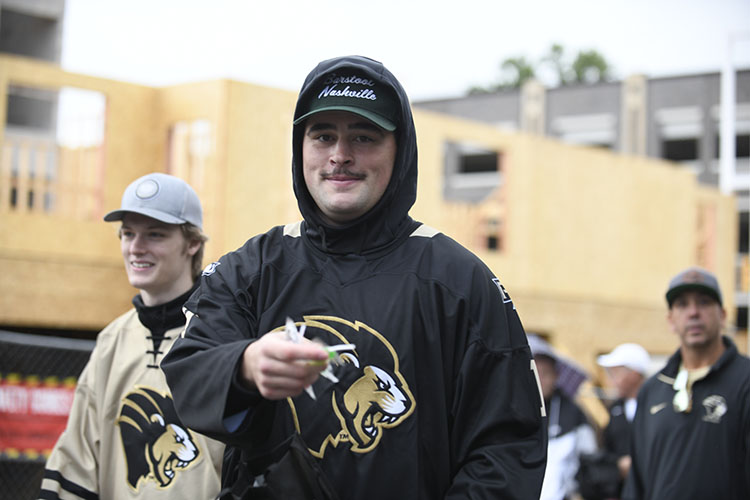 A student in a PNW athletics sweatshirt and baseball cap hands out candy