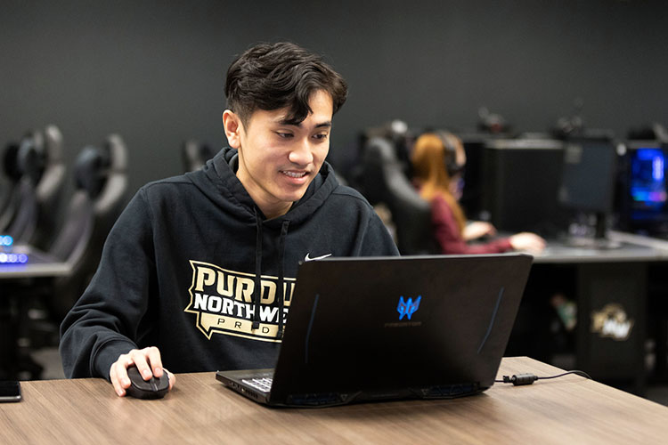 A PNW student clicks a laptop in the Esports Arena.