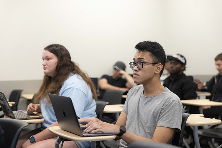 Students sit in a classroom at individual desks.