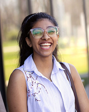 A PNW international student in glasses laughs outdoors.