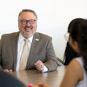 PNW chancellor Chris Holford talks with students at a conference table.