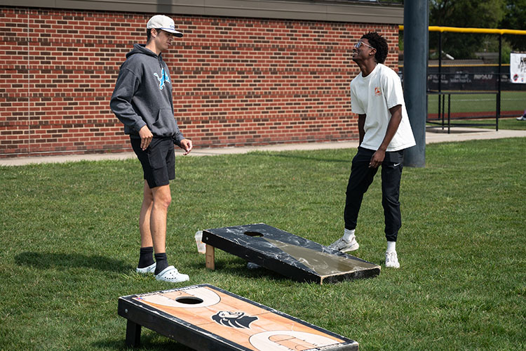 Two students play cornhole