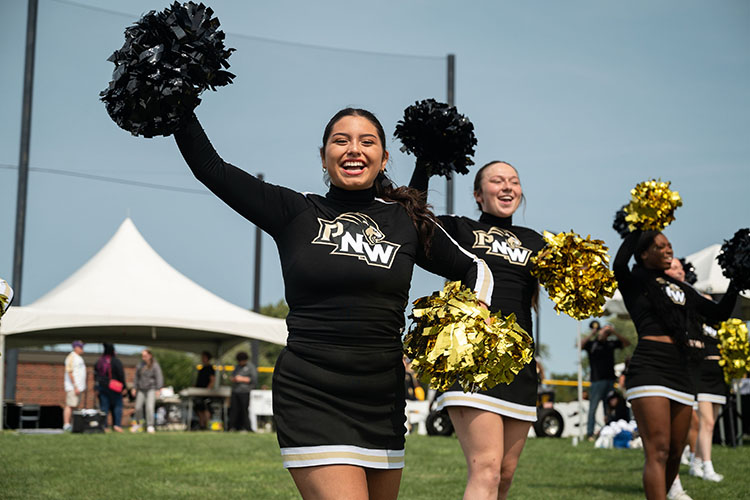 PNW cheerleaders smile and hold black and gold pompoms