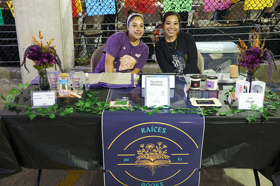 Two vendors pose together at their table.