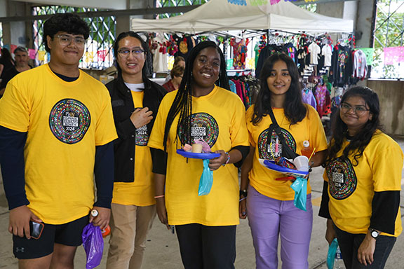 Five students stand together in yellow Hispanic Heritage Month shirts.