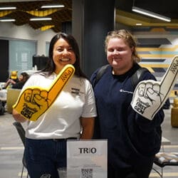 Two people hold up First-Gen foam fingers