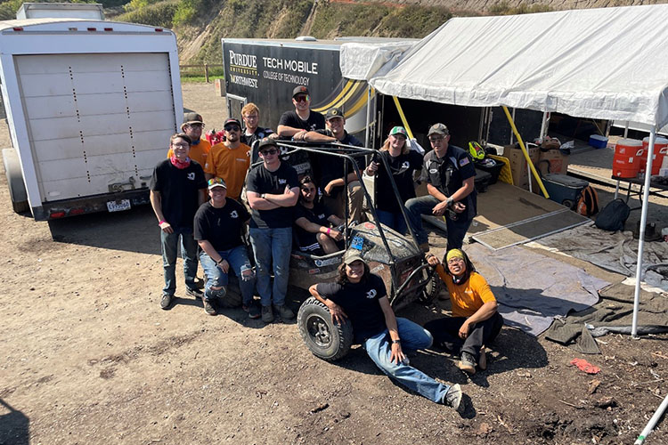 Baja team members pose around their off-road vehicle.