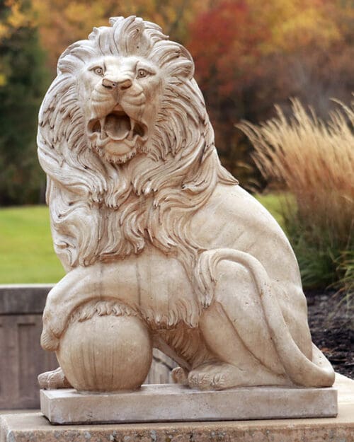 A statue of a lion in front of fall foliage