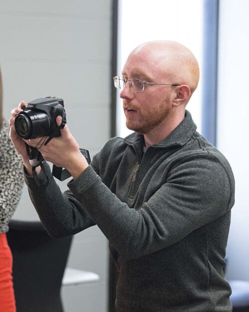 A PNW staff member looks through a camera.