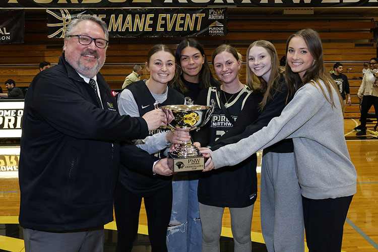 Chancellor Holford hands a trophy to 5 students on the Student Athlete Advisory Committee.