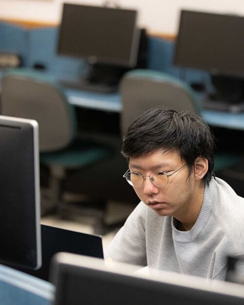 A student sits at a desktop computer