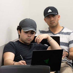 Students sit in class with open laptops in front of them.