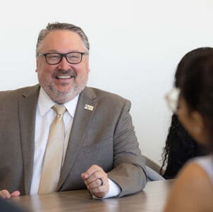 PNW chancellor Chris Holford talks with students at a conference table.