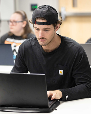 A student in a black long sleeve shirt works at a computer